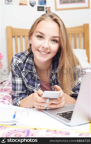 Portrait Of Teenage Girl Using Mobile Phone Whilst Doing Homework