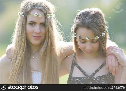 Portrait of teenage girls wearing daisy chain headdresses in park