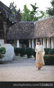Portrait of Thai female with traditional Thai dress walking with temple background