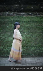 Portrait of Thai female with traditional Thai dress walking with temple background