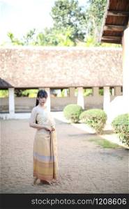 Portrait of Thai female with traditional Thai dress with temple background
