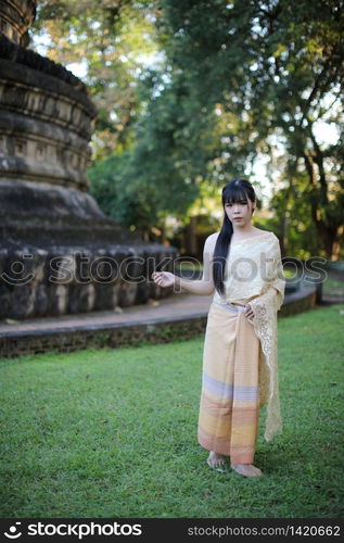 Portrait of Thai female with traditional Thai dress with temple background