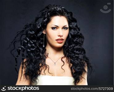 Portrait of the beautiful fashion woman with long curly hairstyle poses indoor