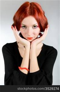 Portrait of the beautiful red-haired girl on a gray background