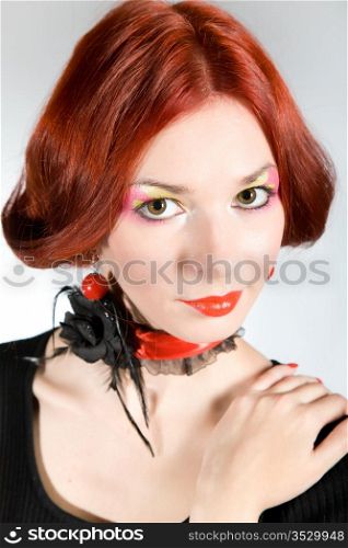 Portrait of the beautiful red-haired girl on a gray background