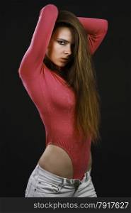 Portrait of the beautiful young sexy woman with long hair posing at studio dressed in the jeans