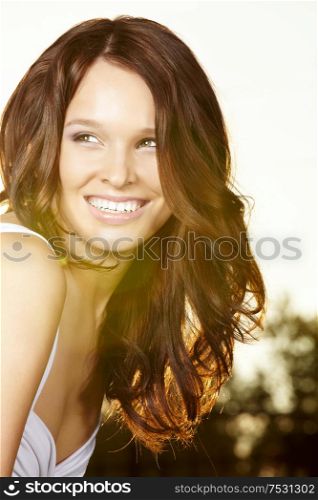 Portrait of the curly beautiful woman in sunlight beams