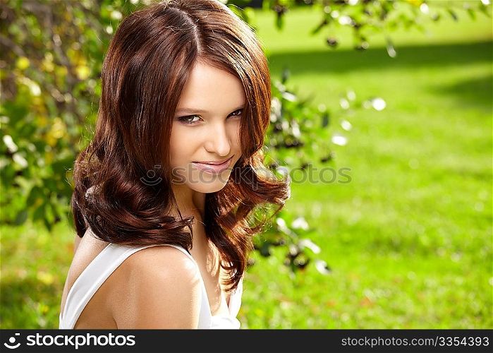 Portrait of the delightful curly young woman in a summer garden