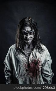 Portrait of the horror zombie woman with bloody face against the black background. Zombie woman with bloody face