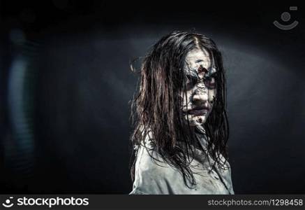Portrait of the horror zombie woman with bloody face against the black background. Halloween. Scary.. Zombie woman with bloody face