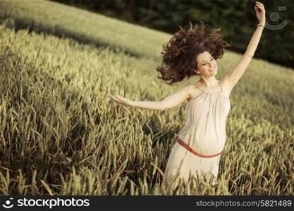 Portrait of the joyful pregnant lady among the cereal crop