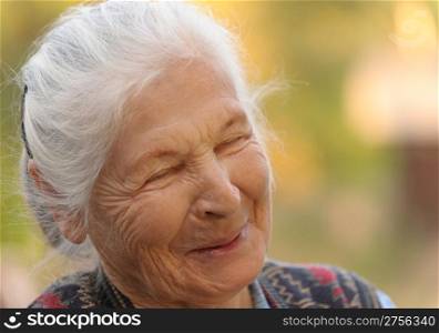 Portrait of the laughing elderly woman. A photo on outdoors