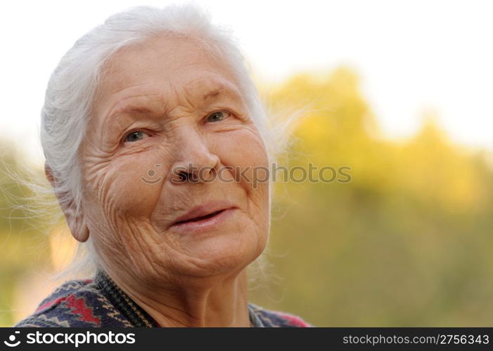 Portrait of the laughing elderly woman. A photo on outdoors