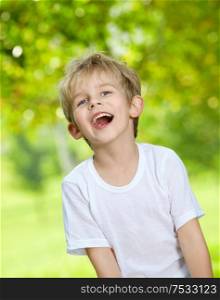 Portrait of the laughing loudly boy against a summer garden
