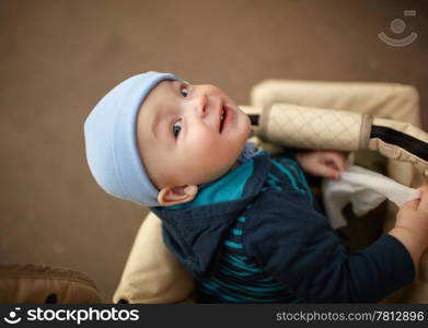 Portrait of the little boy sitting in the buggy and looking to the camera. Natural light, real colors, shallow DOF (prime 35mm L lense).