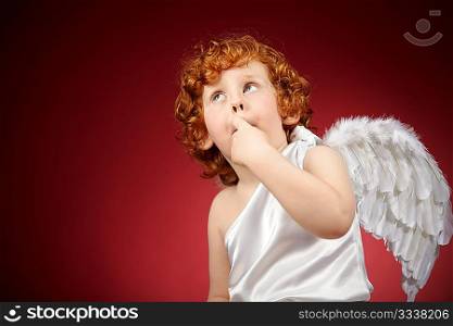 Portrait of the little boy with wings behind the back on a red background