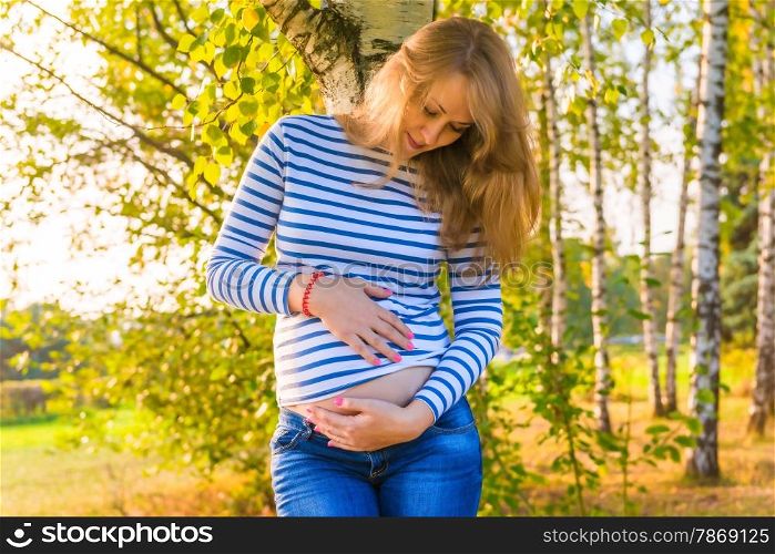 Portrait of the pregnant beautiful girl in the autumn park