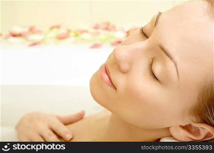 Portrait of the relaxing girl in a bath with petals of roses