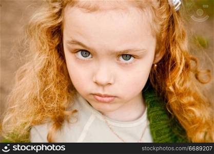 Portrait of the serious grey-eyed little girl with the long hair, looking in a shot