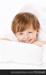 Portrait of the smiling little boy in the bed, isolated