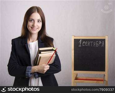 Portrait of the teacher. In the hands of the teacher&#39;s books and pointer. The teacher in the background stands the Board where it is written on September 1