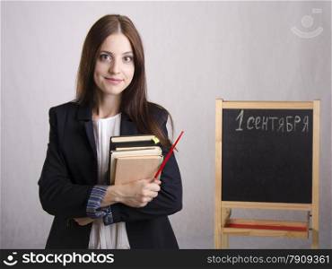 Portrait of the teacher. In the hands of the teacher&#39;s books and pointer. The teacher in the background stands the Board where it is written on September 1