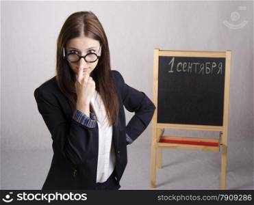 Portrait of the teacher. In the hands of the teacher&#39;s pointer. The teacher corrects points one finger. The teacher in the background stands the Board where it is written on September 1
