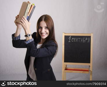 Portrait of the teacher, who raised her with enthusiasm over the head stack of textbooks. In the background stands the Board with the inscription 1 September