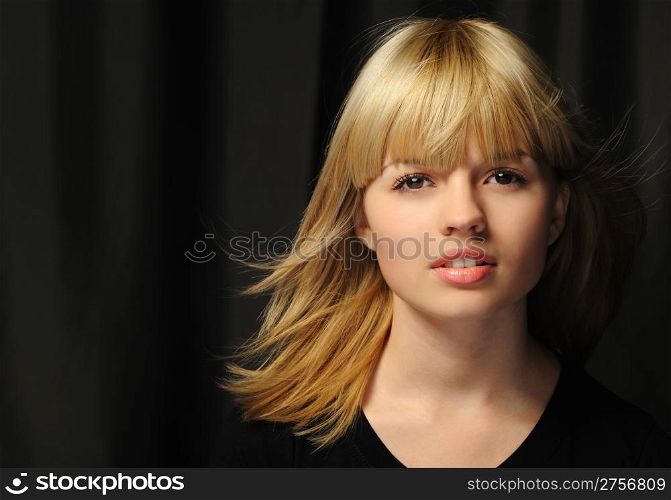 "Portrait of the young attractively girl. Hair of "wheaten" color. A dark back"