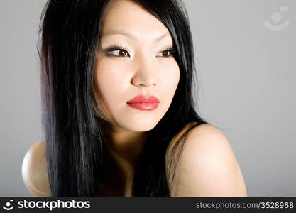 Portrait of the young beautiful brunette on a grey background