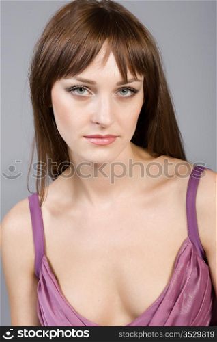 Portrait of the young beautiful brunette on a grey background