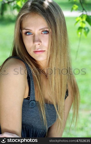 Portrait of the young beautiful woman on a background of leaves of a birch