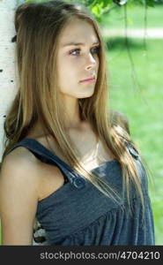 Portrait of the young beautiful woman on a background of leaves of a birch