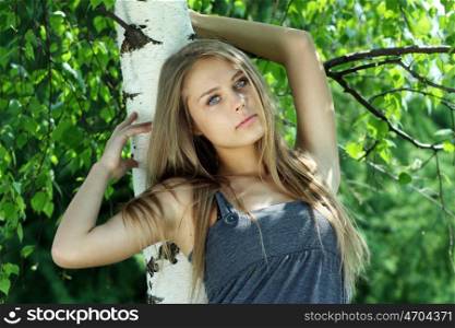 Portrait of the young beautiful woman on a background of leaves of a birch