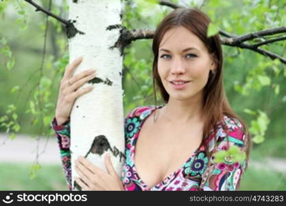 Portrait of the young beautiful woman on a background of leaves of a birch