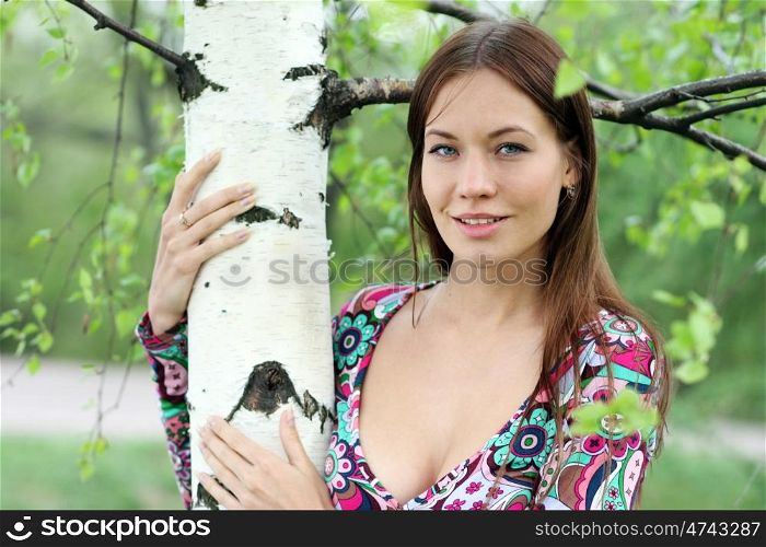 Portrait of the young beautiful woman on a background of leaves of a birch