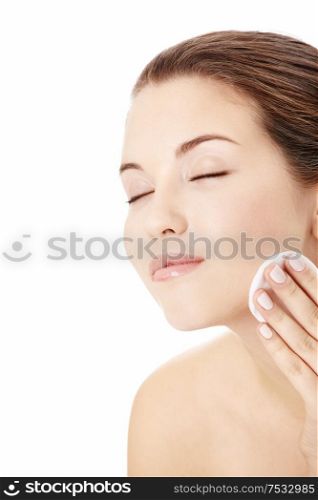 Portrait of the young girl applying on a face a cosmetic pad, isolated
