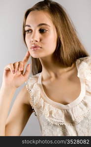 Portrait of the young long-haired girl in an elegant dress on a gray background