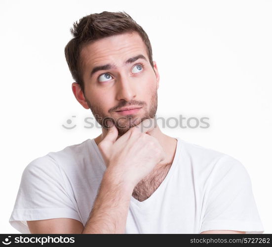 Portrait of the young thinking man looks up in casuals isolated on white background.