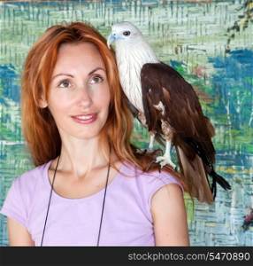 Portrait of the young woman with a prey bird on a shoulder.