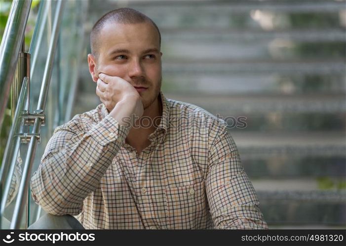 Portrait of thinking businessman sitting on stairs at office building