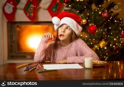 Portrait of thoughtful girl in Santa cap thinking of letter with gift wishes