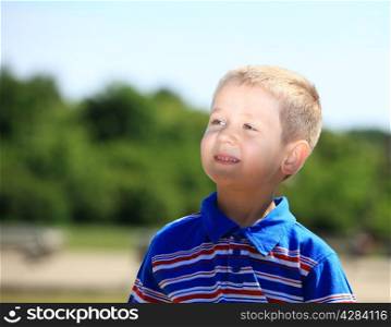 Portrait of thoughtful, pensive little boy child or kid in summer park