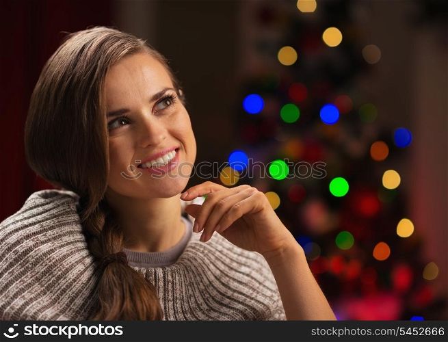 Portrait of thoughtful woman with Christmas tree in background
