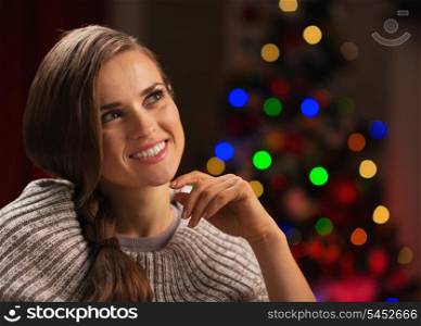 Portrait of thoughtful woman with Christmas tree in background