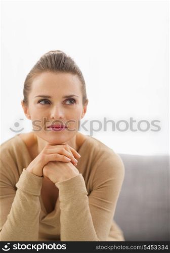 Portrait of thoughtful young housewife sitting on sofa