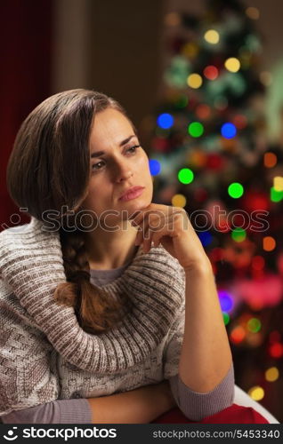 Portrait of thoughtful young woman in front of christmas lights