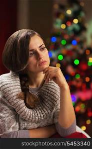 Portrait of thoughtful young woman in front of christmas lights