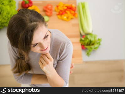 Portrait of thoughtful young woman in kitchen