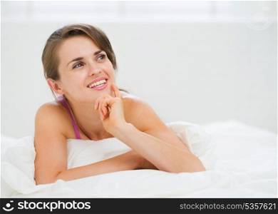 Portrait of thoughtful young woman laying on bed